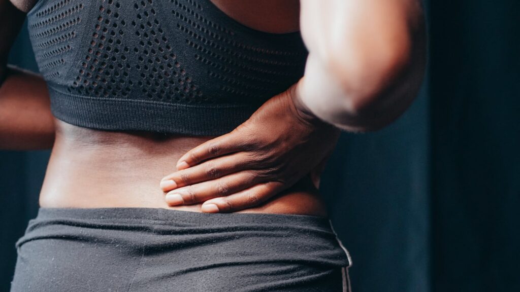 Persona sosteniendo la zona lumbar con dolor de espalda como imagen educativa para artículo sobre Ayurveda