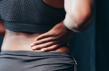 Persona sosteniendo la zona lumbar con dolor de espalda como imagen educativa para artículo sobre Ayurveda