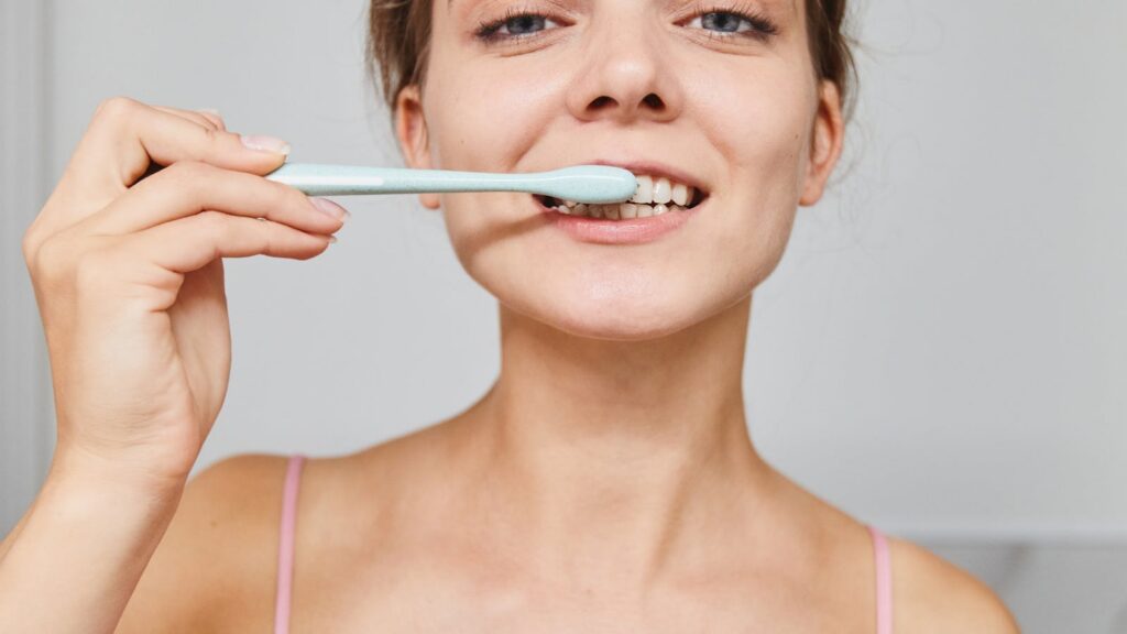 Mujer cepillándose los dientes como imagen educativa para artículo sobre mal aliento y Ayurveda