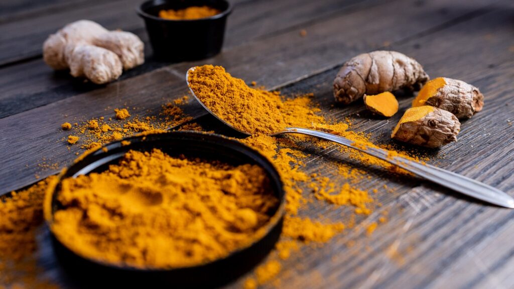 Cúrcuma en polvo y raíz como imagen educativa sobre pasta tópica tradicional en Ayurveda
