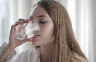 Mujer tomando agua como imagen educativa sobre hidratación y salud de la vejiga