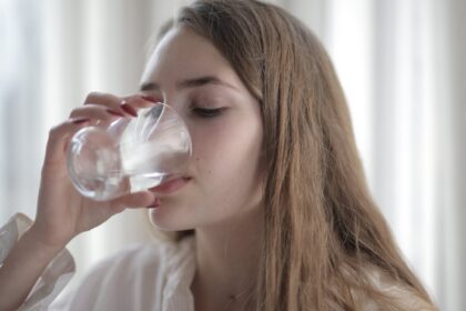Hidratación y salud urinaria – imagen destacada Mujer tomando agua como imagen educativa sobre hidratación y salud de la vejiga