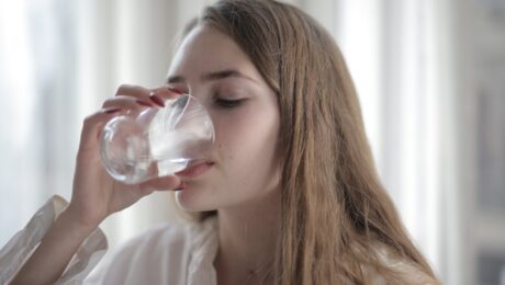 Mujer tomando agua como imagen educativa sobre hidratación y salud de la vejiga