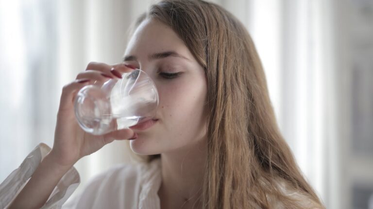 Mujer tomando agua como imagen educativa sobre hidratación y salud de la vejiga