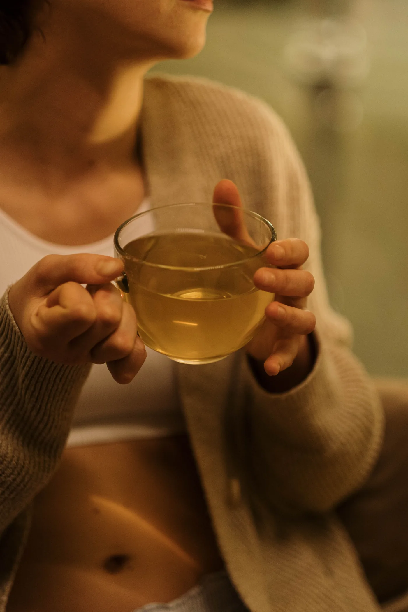 Persona sosteniendo una taza de infusión tibia durante la noche