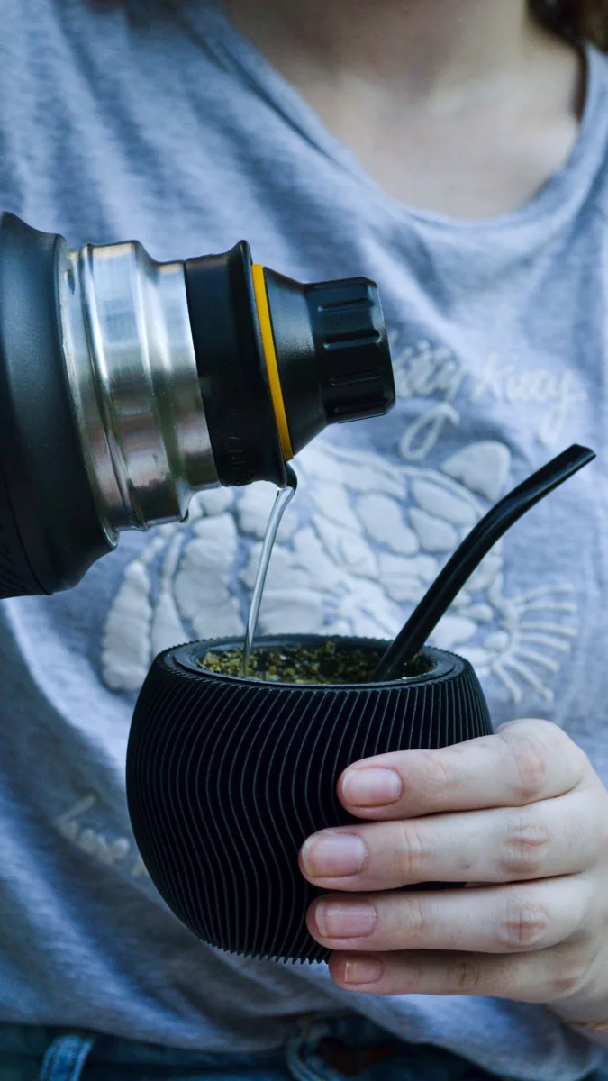 Persona cebando un mate con agua desde un termo