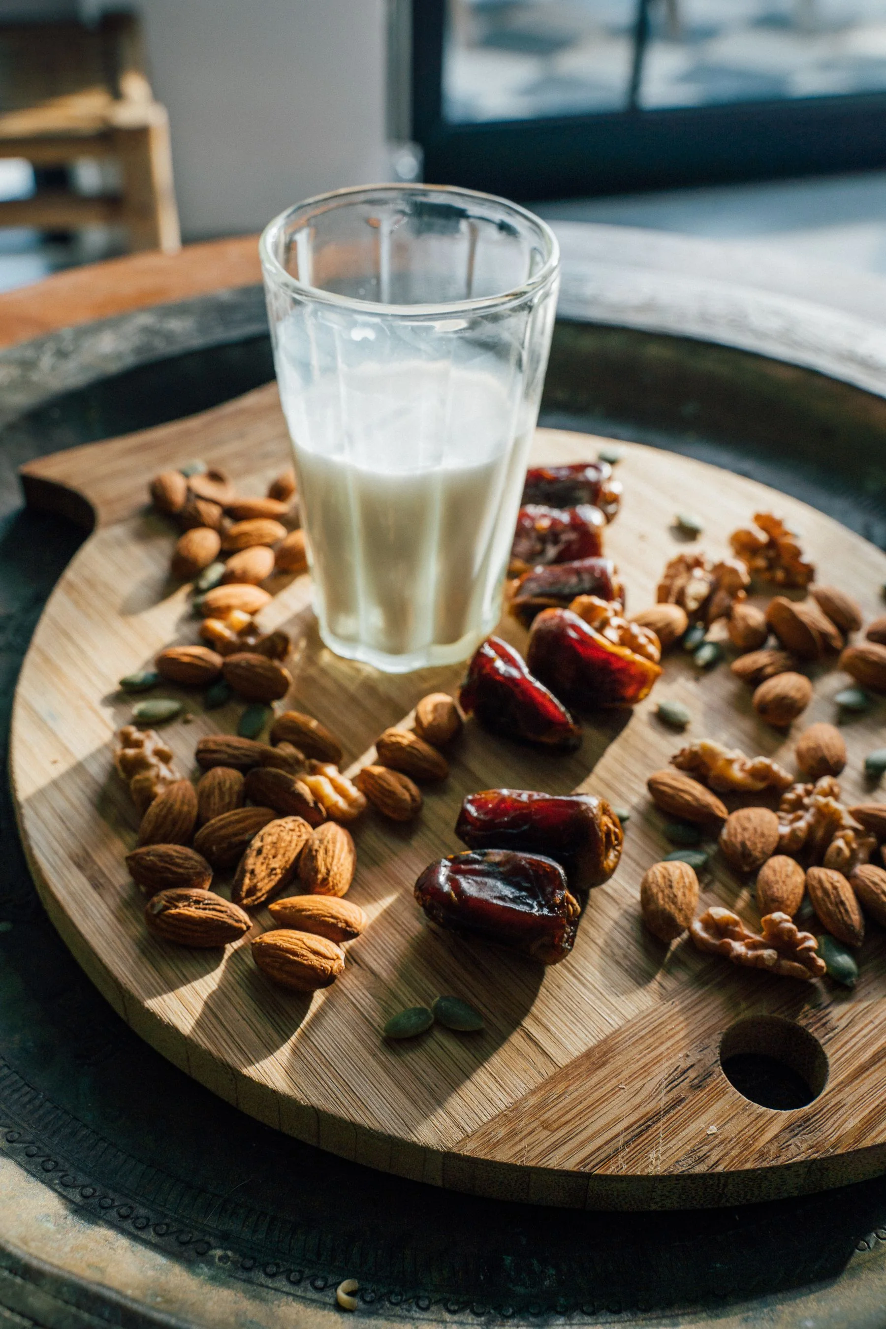 Vaso de leche con almendras y dátiles sobre una tabla de madera como símbolo de nutrición