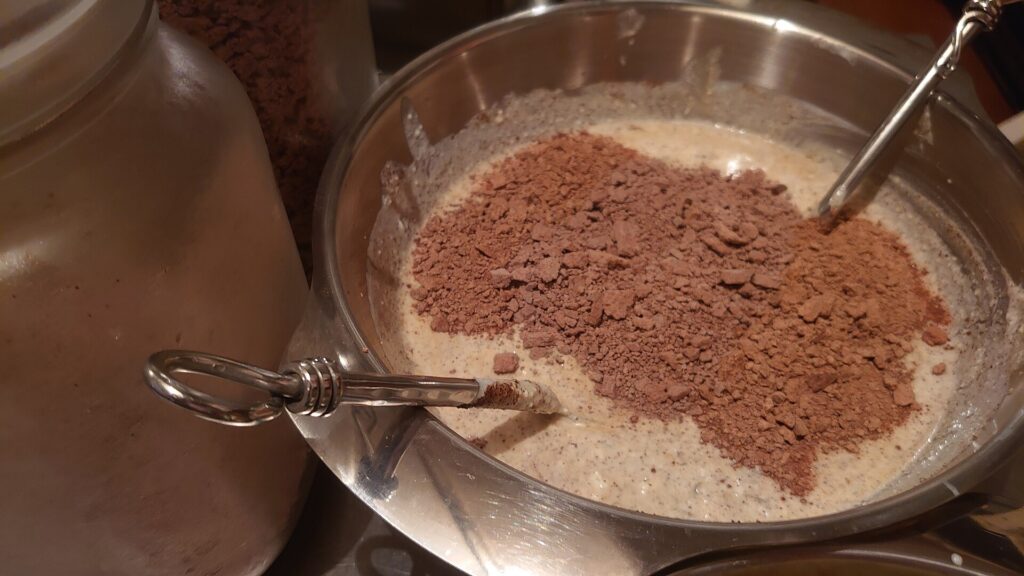 Homemade Yogurt in a stainless steel bowl for family sharing mixed with Cacao mass flakes and powdered fruit mix. The cacao mass was previously liquid before processed into flakes.