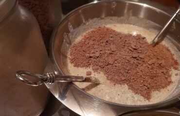 Homemade Yogurt in a stainless steel bowl for family sharing mixed with Cacao mass flakes and powdered fruit mix. The cacao mass was previously liquid before processed into flakes.