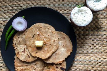 A traditional Punjabi meal consisting of aloo paratha topped with butter and served alongside a glass of fresh lassi. Photograph taken as part of Wiki Loves Food 2021.