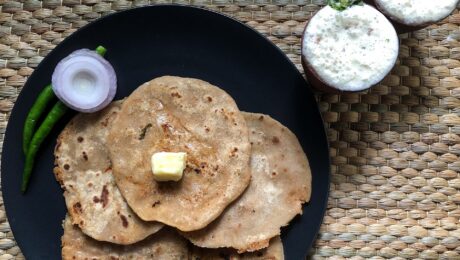 A traditional Punjabi meal consisting of aloo paratha topped with butter and served alongside a glass of fresh lassi. Photograph taken as part of Wiki Loves Food 2021.