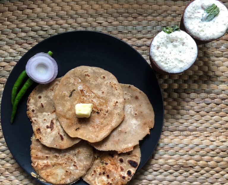 A traditional Punjabi meal consisting of aloo paratha topped with butter and served alongside a glass of fresh lassi. Photograph taken as part of Wiki Loves Food 2021.