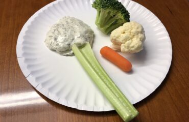 A paper plate holding a celery stick, a piece of broccoli, a piece of cauliflower, a baby carrot and some dipping sauce in the Dulles section of Sterling, Loudoun County, Virginia