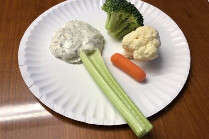 A paper plate holding a celery stick, a piece of broccoli, a piece of cauliflower, a baby carrot and some dipping sauce in the Dulles section of Sterling, Loudoun County, Virginia