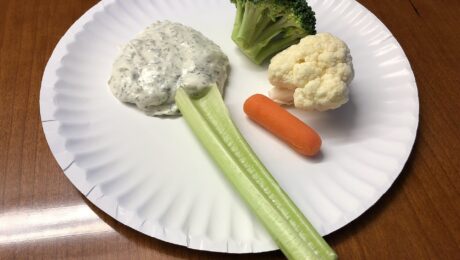A paper plate holding a celery stick, a piece of broccoli, a piece of cauliflower, a baby carrot and some dipping sauce in the Dulles section of Sterling, Loudoun County, Virginia